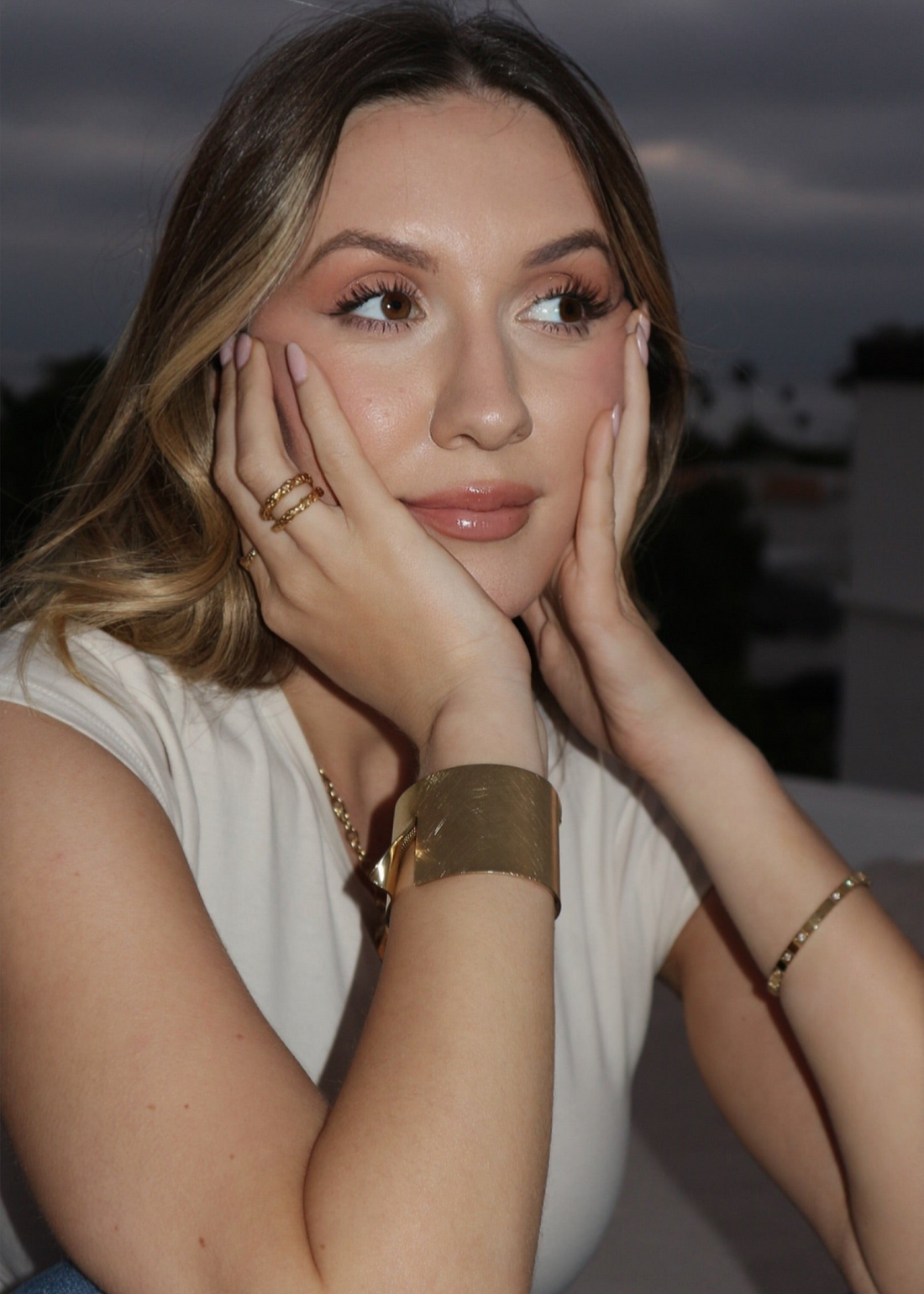 Woman with hands on face against a blurred outdoor background