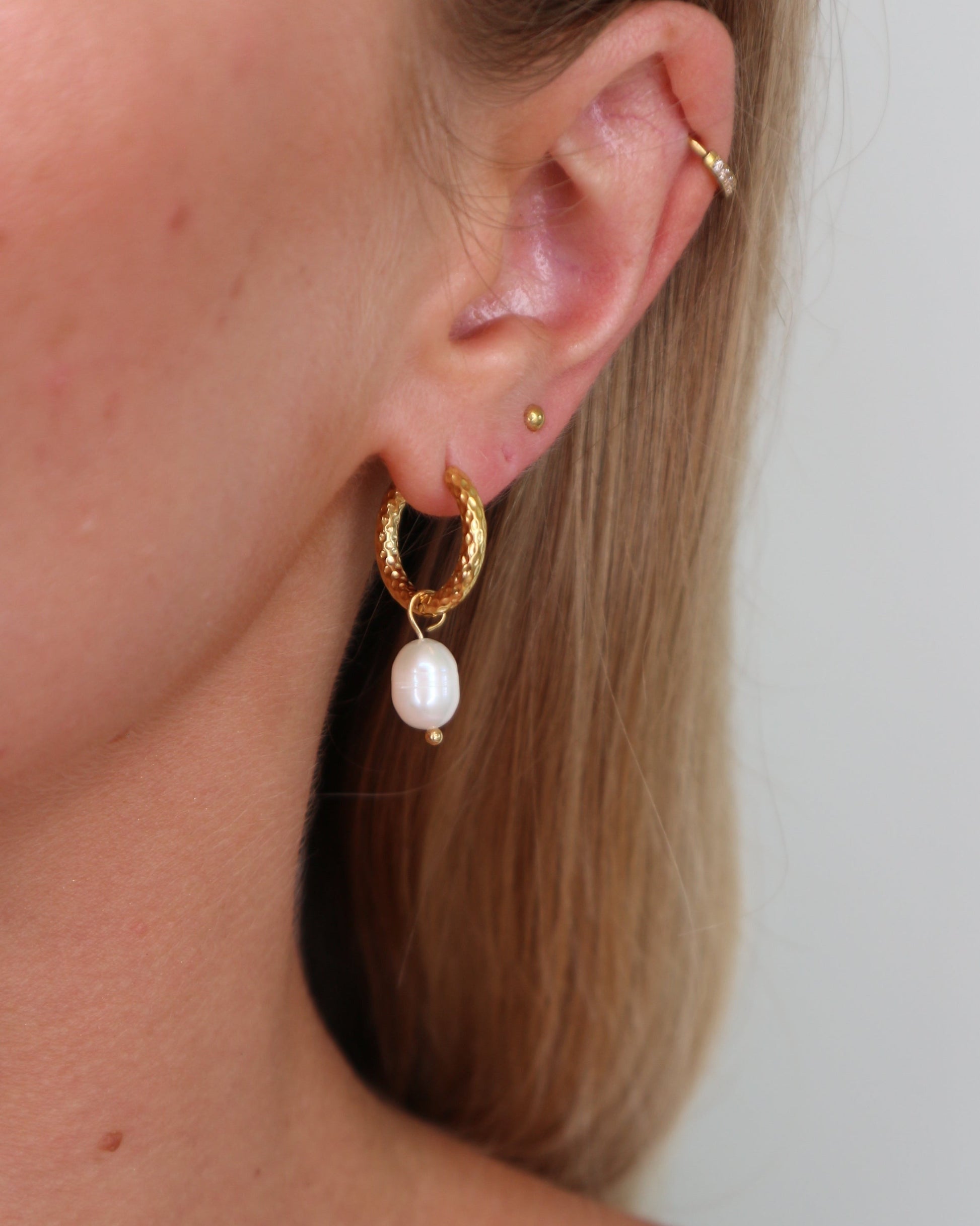 Close up on huggie earrings with attached pearl