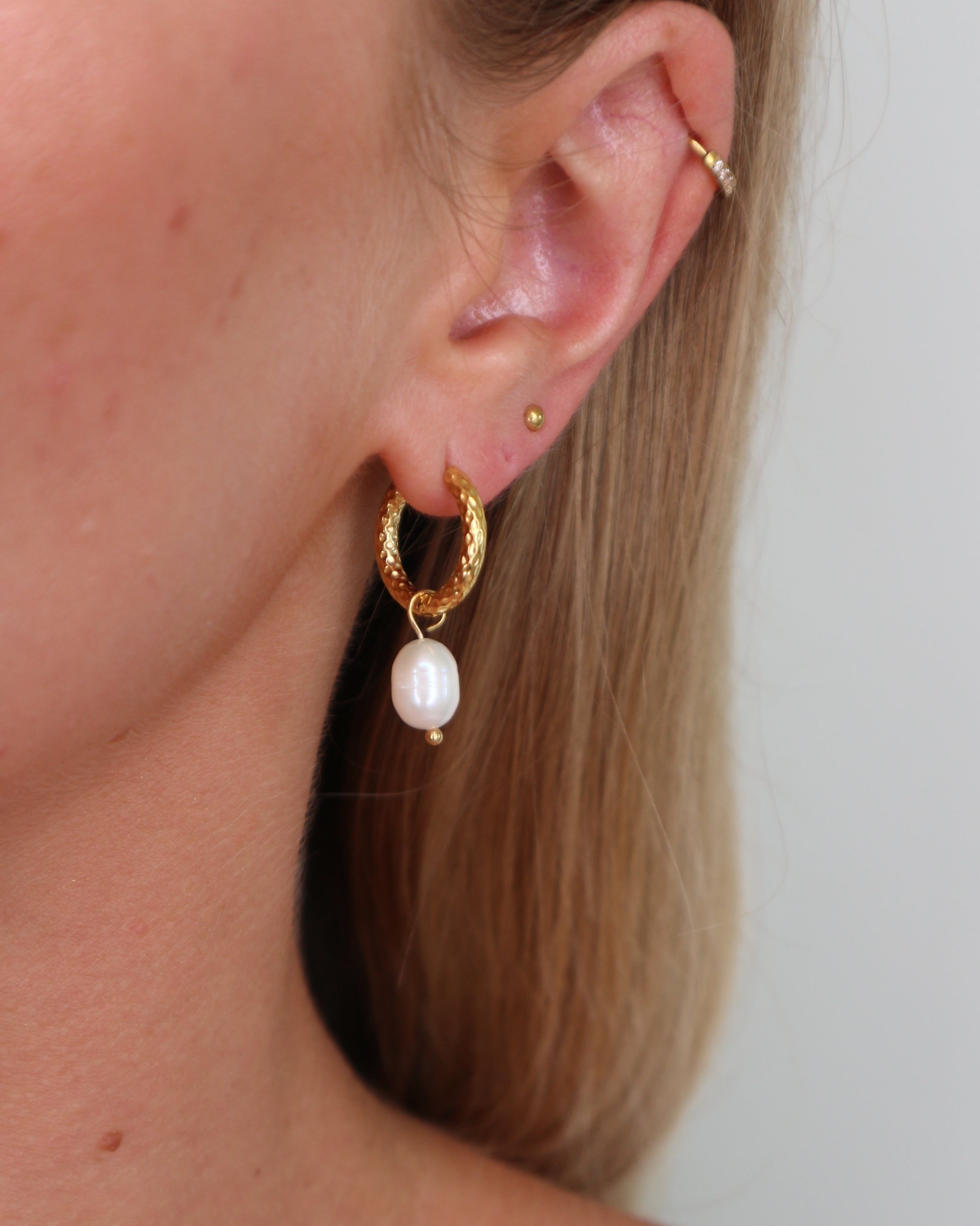 Close up on huggie earrings with attached pearl