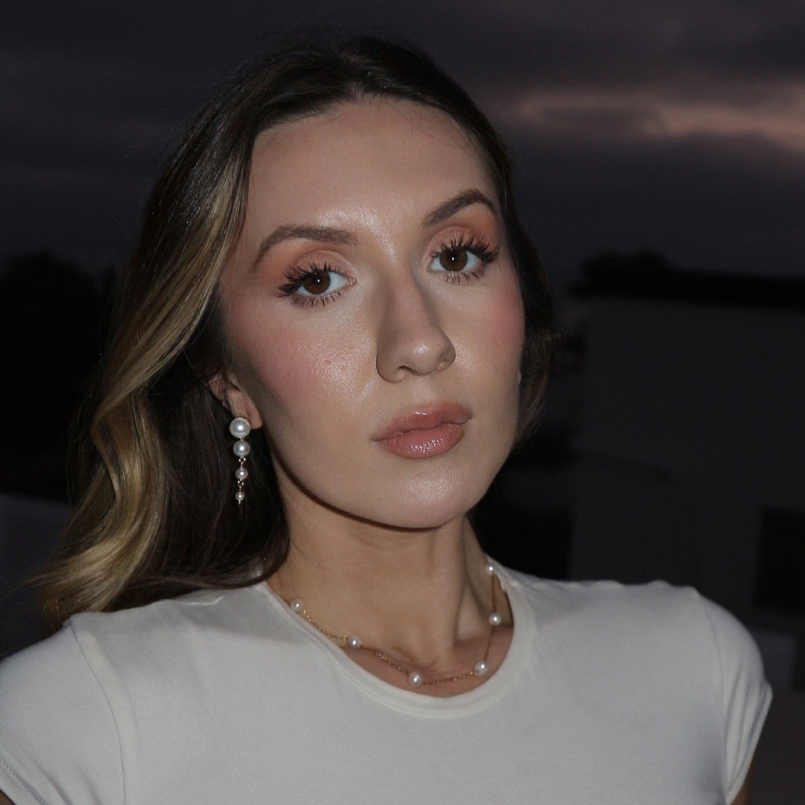 Woman wearing a white top against a dark background
