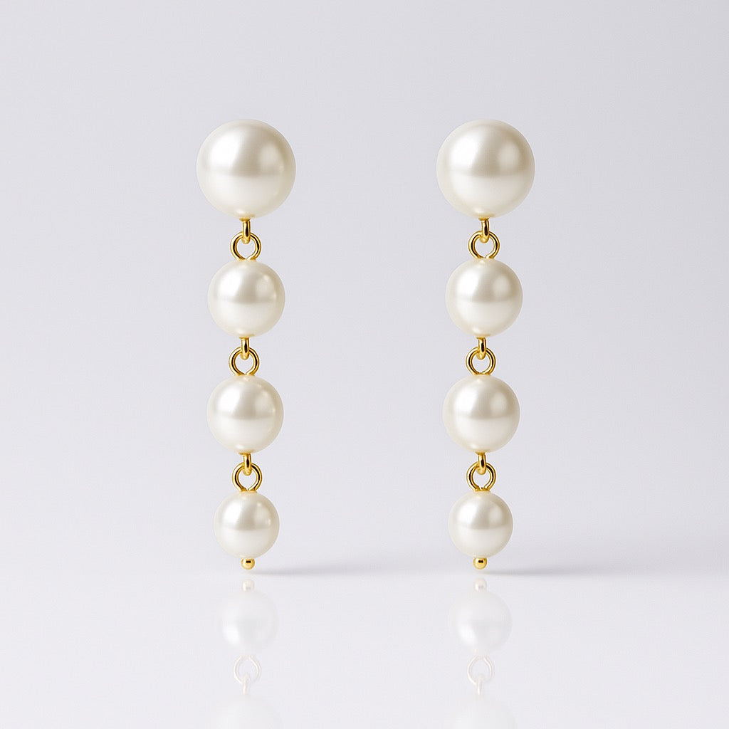 Pearl earrings with gold clasps on a light gray background