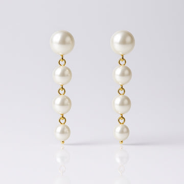 Pearl earrings with gold clasps on a light gray background