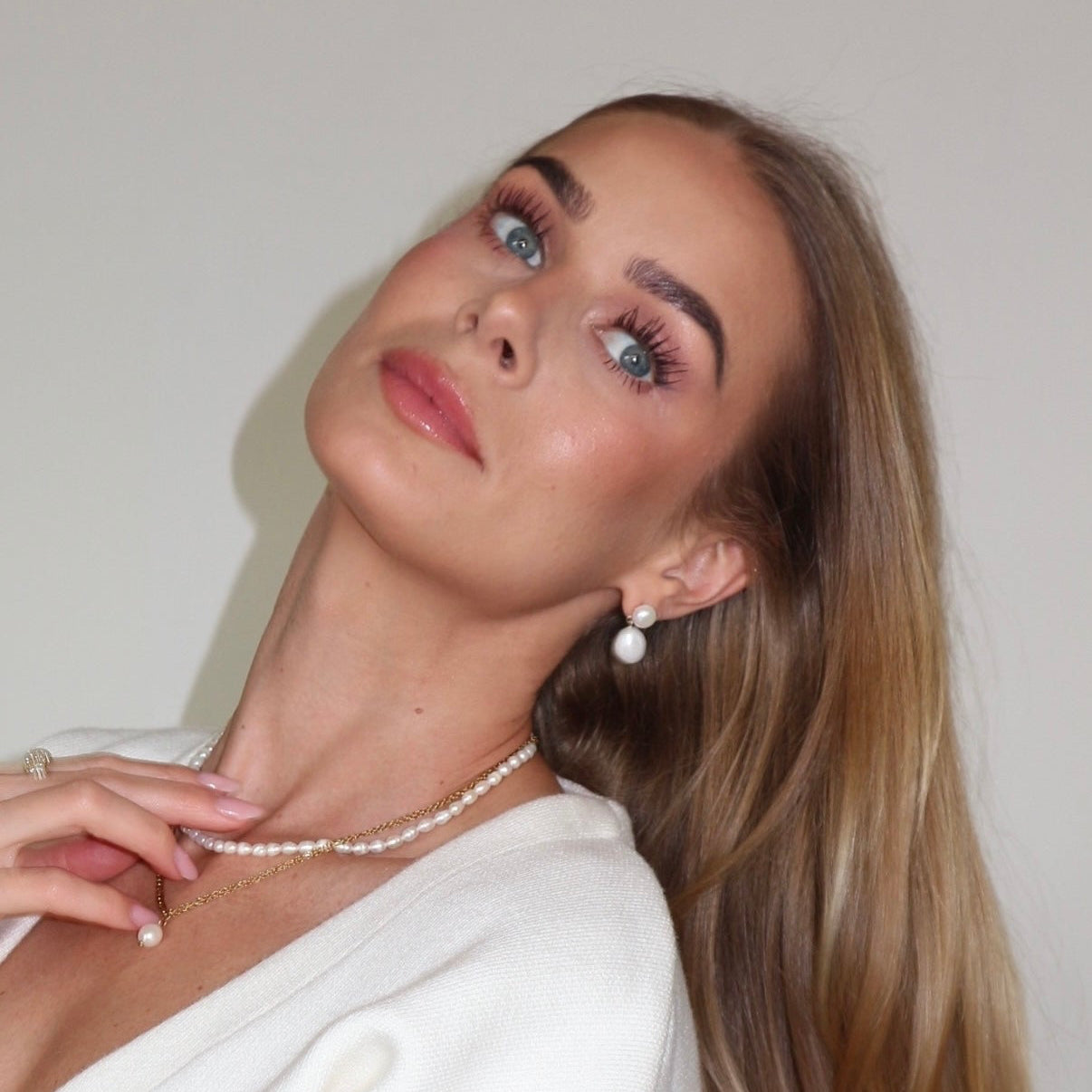 Woman wearing a pearl necklace against a plain background