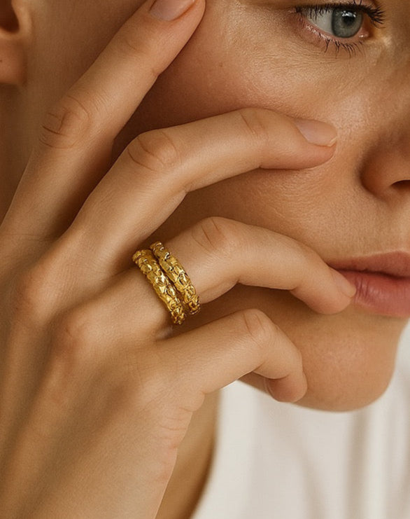 Close-up of a woman's hand with gold rings on a neutral background