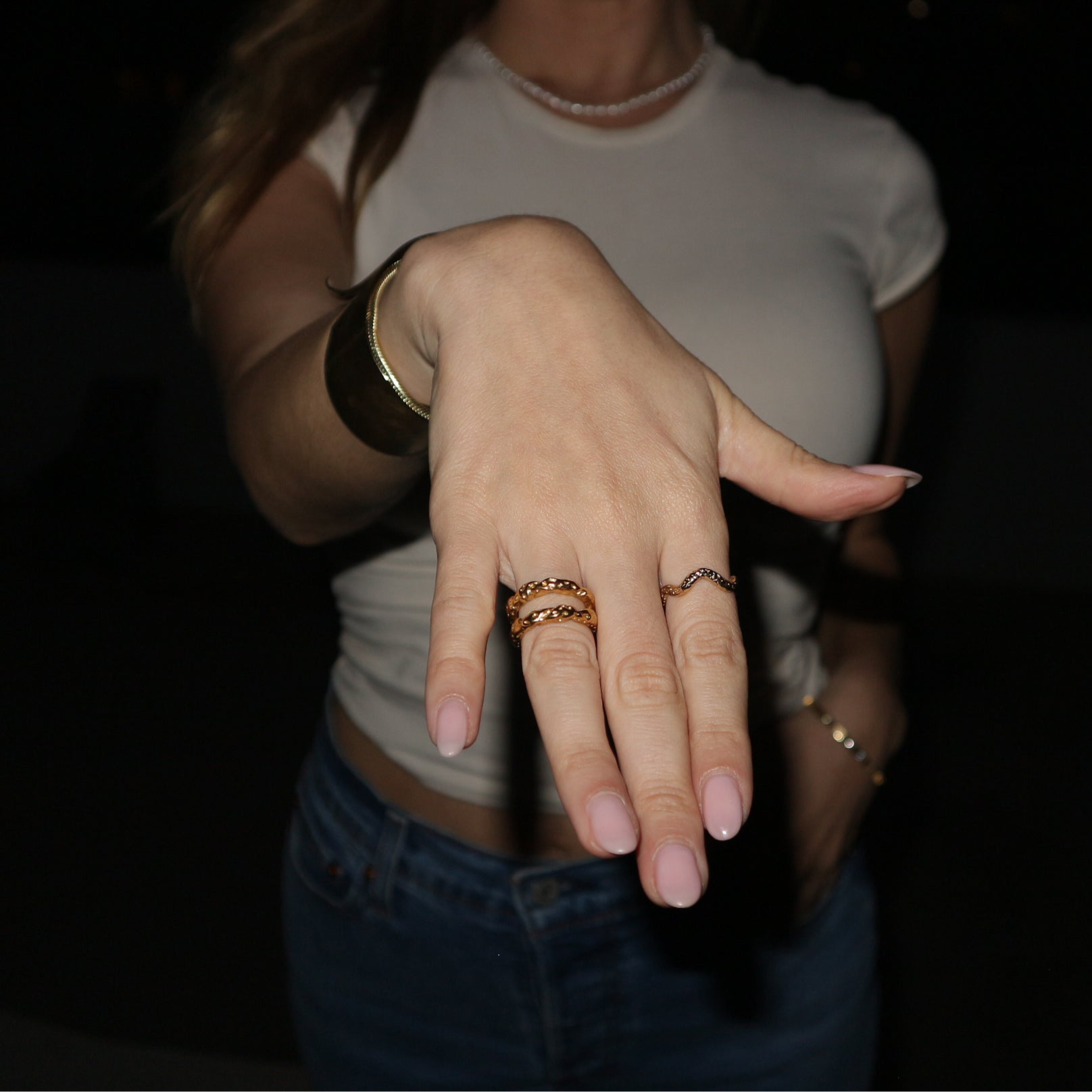 Hand with multiple rings on a dark background